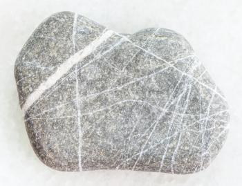 macro shooting of natural mineral rock specimen - pebble of Greywacke sandstone on white marble background