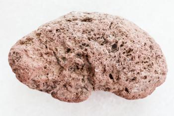 macro shooting of natural mineral rock specimen - red pumice stone on white marble background from Sicily