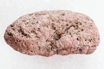 macro shooting of natural mineral rock specimen - pebble of red pumice stone on white marble background from Sicily