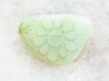 macro shooting of natural mineral rock specimen - tumbled Prasiolite (green quartz) gemstone on white marble background
