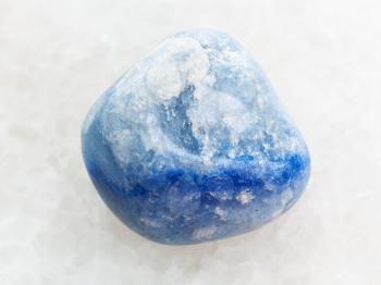 macro shooting of natural mineral rock specimen - polished blue dyed agate gemstone on white marble background