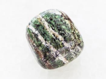 macro shooting of natural mineral rock specimen - polished chrysotile gemstone on white marble background