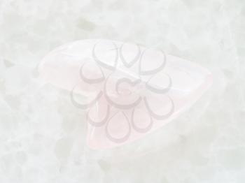 macro shooting of natural mineral rock specimen - polished rose quartz gemstone in heart shape on white marblee background from South Dakota, USA