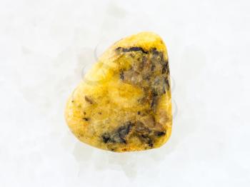 macro shooting of natural mineral rock specimen - polished yellow Agate gemstone on white marble background from Mexico