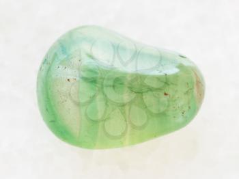 macro shooting of natural mineral rock specimen - polished green Calcite gemstone on white marble background