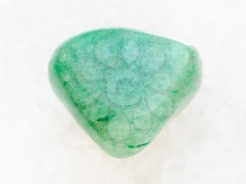 macro shooting of natural mineral rock specimen - tumbled green Aventurine gem on white marble background