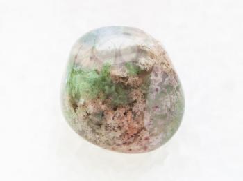 macro shooting of natural mineral rock specimen - polished Moss Agate gemstone on white marble background