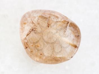 macro shooting of natural mineral rock specimen - Rutilated Quartz gemstone on white marble background