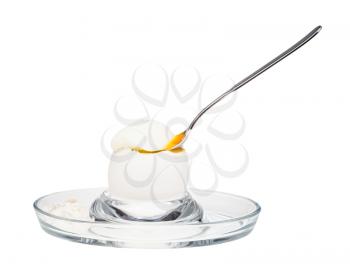 side view of soft-boiled white egg with spoon in glass egg cup isolated on white background