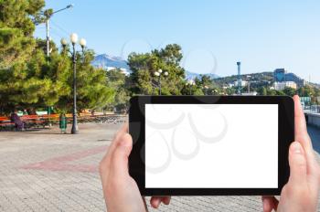 travel concept - tourist photographs Lenin Street Embankment on coast of Black Sea in Alushta city in Crimea in september morning on tablet with cut out screen for advertising logo