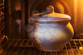 cooking soup - closed ceramic pot with stewed meat in electric oven