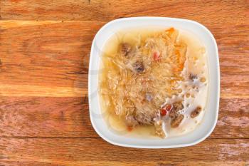 top view of traditional russian cabbage soup with stewed sauerkraut in ceramic plate on wooden table
