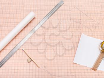 top view of drawing tools for creating of clothing pattern on sheet of graph paper