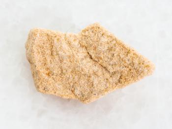 macro shooting of natural mineral rock specimen - rough sandstone stone on white marble background