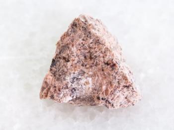 macro shooting of natural mineral rock specimen - raw Granite stone on white marble background