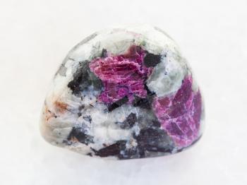 macro shooting of natural mineral stone specimen - polished pink Corundum crystals in rock on white marble background