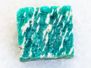 macro shooting of natural mineral rock specimen - rough amazonite stone on white marble background