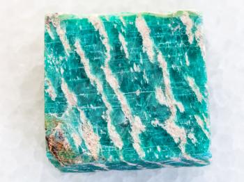 macro shooting of natural mineral rock specimen - raw amazonite stone on white marble background