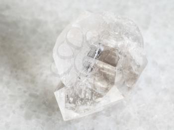 macro shooting of natural mineral rock specimen - rough rock crystal of quartz gemstone on white marble background