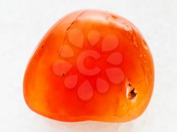 macro shooting of natural mineral rock specimen - polished carnelian gem on white marble background from Madagascar