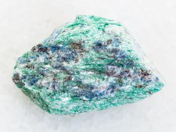 macro shooting of natural mineral rock specimen - rough Fuchsite (chrome mica) stone on white marble background from Hizovaara, Republic of Karelia in Russia