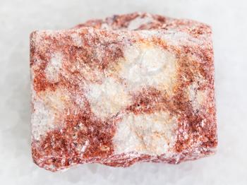 macro shooting of natural mineral rock specimen - rough pink Aventurine stone on white marble background from Verkhneye Dubrovo district of Sverdlovk region, Ural Mountains, Russia