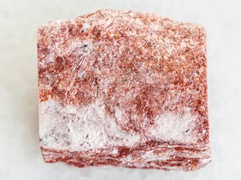macro shooting of natural mineral rock specimen - raw pink Aventurine stone on white marble background from Verkhneye Dubrovo district of Sverdlovk region, Ural Mountains, Russia