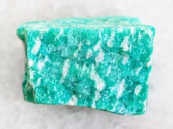 macro shooting of natural mineral rock specimen - rough green amazonite stone on white marble background from Western Keivy, Kola Peninsula, Russia
