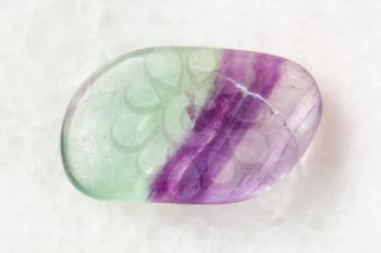 macro shooting of natural mineral rock specimen - polished Fluorite gem stone on white marble background