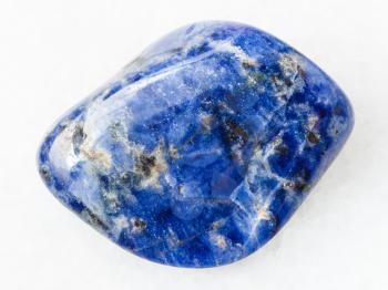 macro shooting of natural mineral rock specimen - tumbled Sodalite gemstone on white marble background from Bolivia