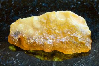 macro shooting of natural mineral rock specimen - rough baltic Amber stone on dark granite background from Latvia