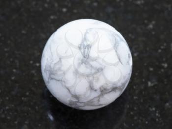 macro shooting of natural mineral rock specimen - bead from Howlite gemstone on dark granite background