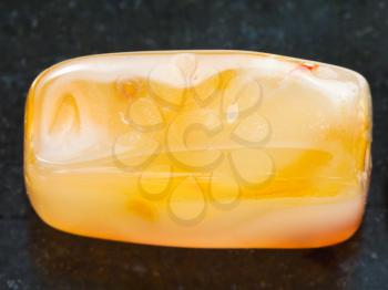 macro shooting of natural mineral rock specimen - bead from yellow Agate gemstone on dark granite background