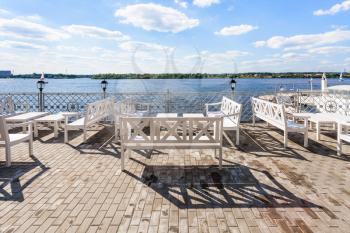 empty benches and tables on waterfront of Klyazma river water reservoir of Moscow Canal in summer day