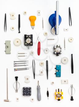 watchmaker workshop - vertical pattern from various watch repairing tools on white background