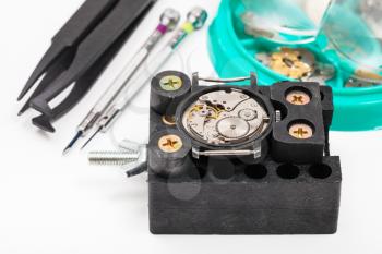 watchmaker workshop - holder with wristwatch and tools for repairing watch close up on white background