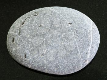 macro shooting of natural mineral rock specimen - tumbled Graywacke sandstone on dark granite background