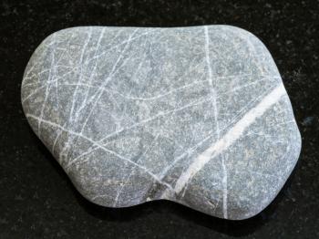 macro shooting of natural mineral rock specimen - pebble of Graywacke sandstone on dark granite background