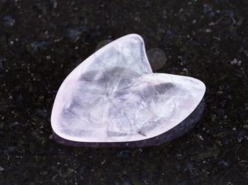 macro shooting of natural mineral rock specimen - tumbled rose quartz gemstone in heart shape on dark granite background from South Dakota, USA