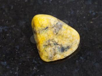macro shooting of natural mineral rock specimen - polished yellow Agate gemstone on dark granite background from Mexico