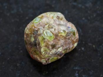 macro shooting of natural mineral rock specimen - polished Peridot gemstone on dark granite background