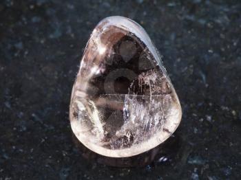 macro shooting of natural mineral rock specimen - polished smoky quartz gemstone on dark granite background