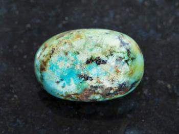 macro shooting of natural mineral rock specimen - polished turquoise gemstone on dark granite background