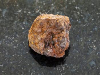 macro shooting of natural mineral rock specimen - raw limonite (iron ore) stone on dark granite background