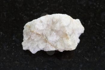 macro shooting of natural mineral rock specimen - scheelite vein (tungsten ore) in rough stone on dark granite background