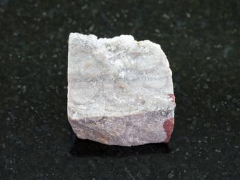 macro shooting of natural mineral rock specimen -Rhyolite stone on dark granite background