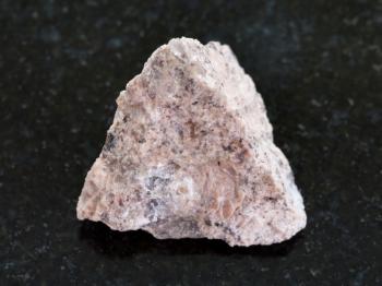 macro shooting of natural mineral rock specimen - rough Granite stone on dark granite background