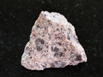 macro shooting of natural mineral rock specimen - raw Granite stone on dark granite background