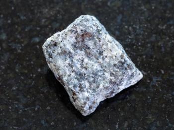 macro shooting of natural mineral rock specimen - raw Gabbro stone on dark granite background