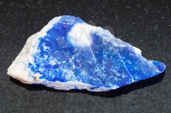 macro shooting of natural mineral rock specimen - raw lazurite (lapis lazuli) stone on dark granite background